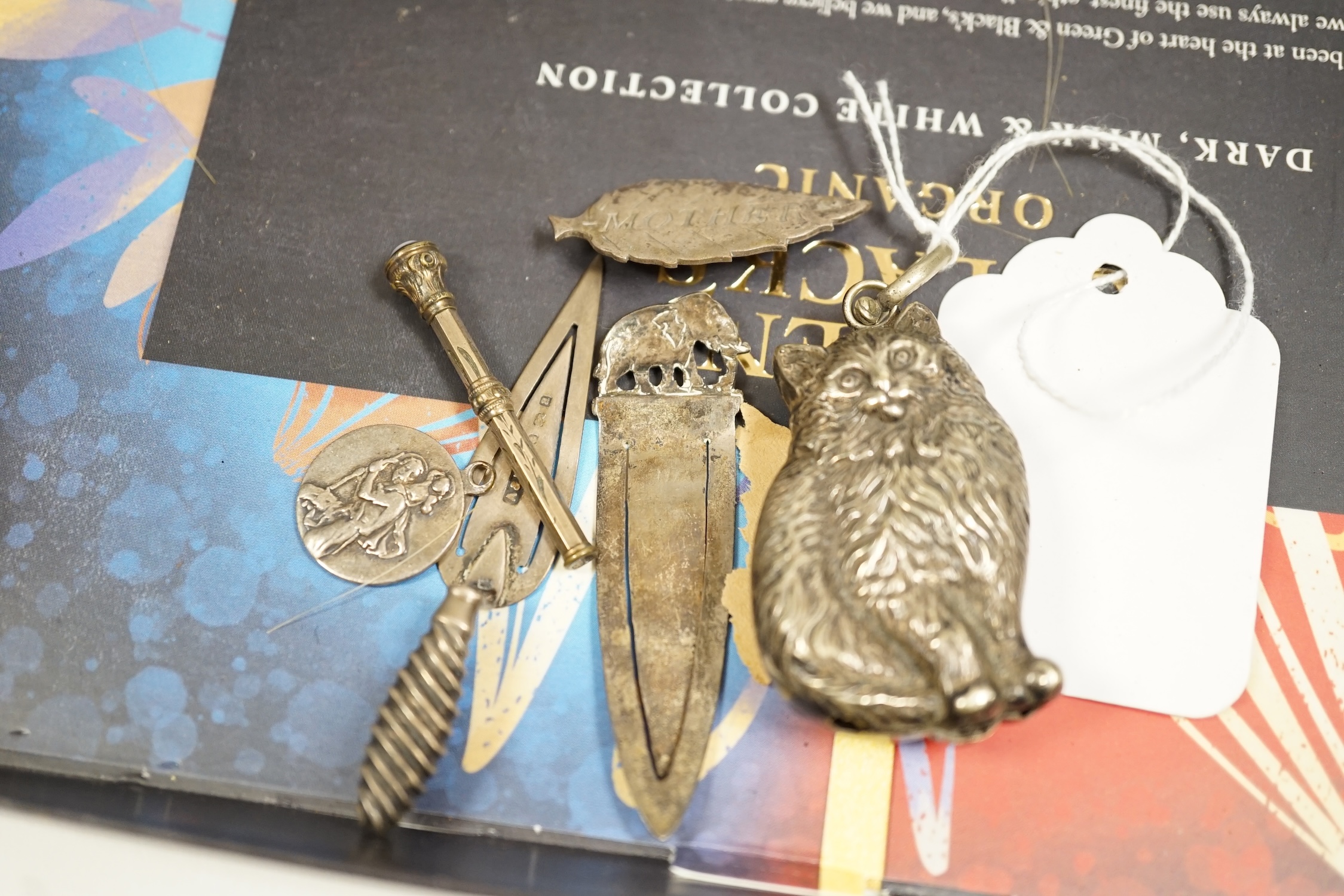 A collection of mostly silver items to include a rattle in the form of a cat, a vesta case, silver backed brushes and a bookmark in form a of trowel, largest 16.5cm wide. Condition - poor to fair